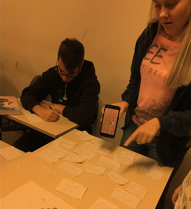 Alunos projetando com cartões e um celular sobre a mesa