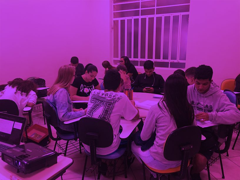 Turma de jovens trabalhando em grupos nas mesas
