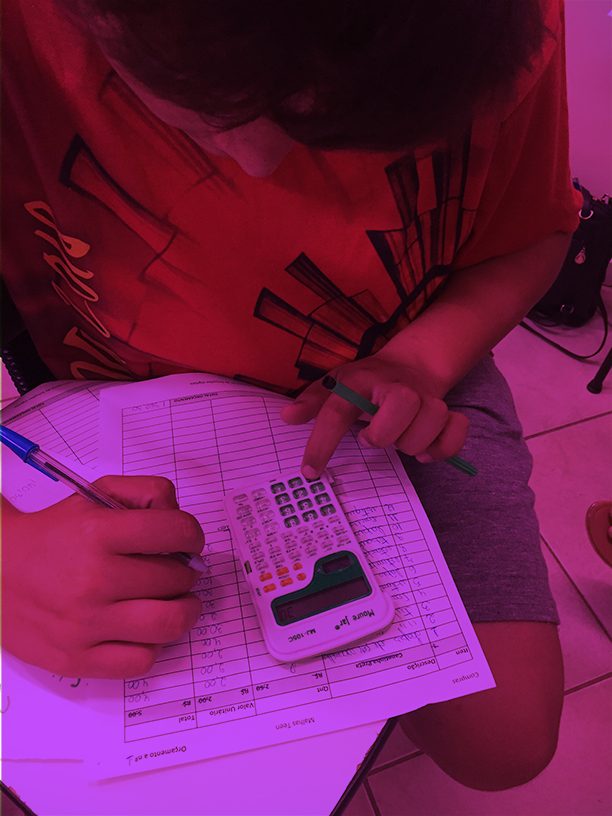 Aluna fazendo cálculos em uma folha com calculadora